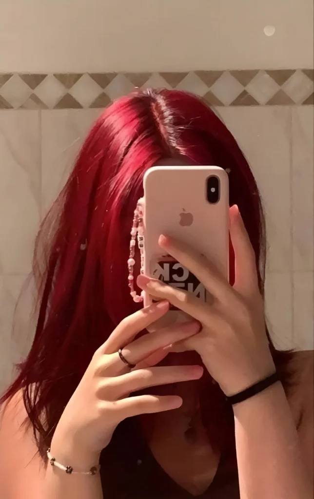 Person with bright, cherry-red burgundy hair, partially obscuring their face.