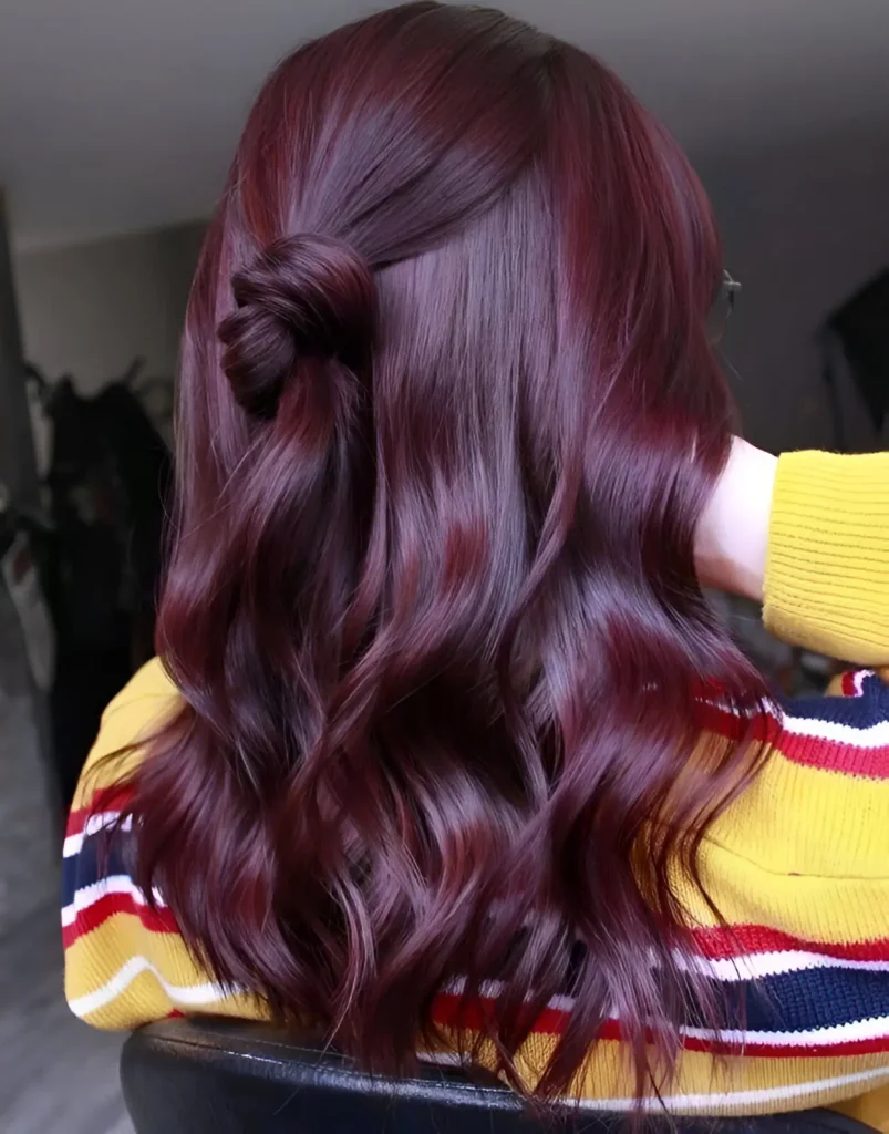 Person with medium-length, wavy, dark cherry cola burgundy hair, viewed from the back.