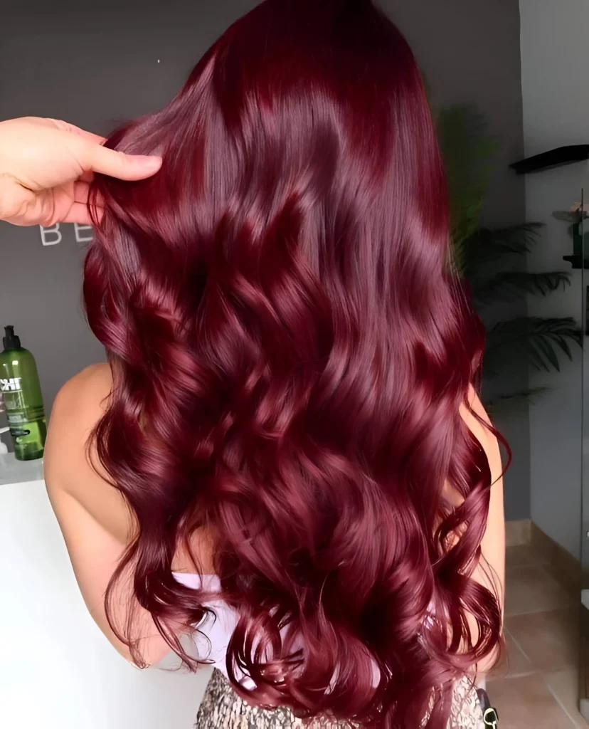 Person with long, ruby red burgundy hair styled in defined curls, viewed from the back.