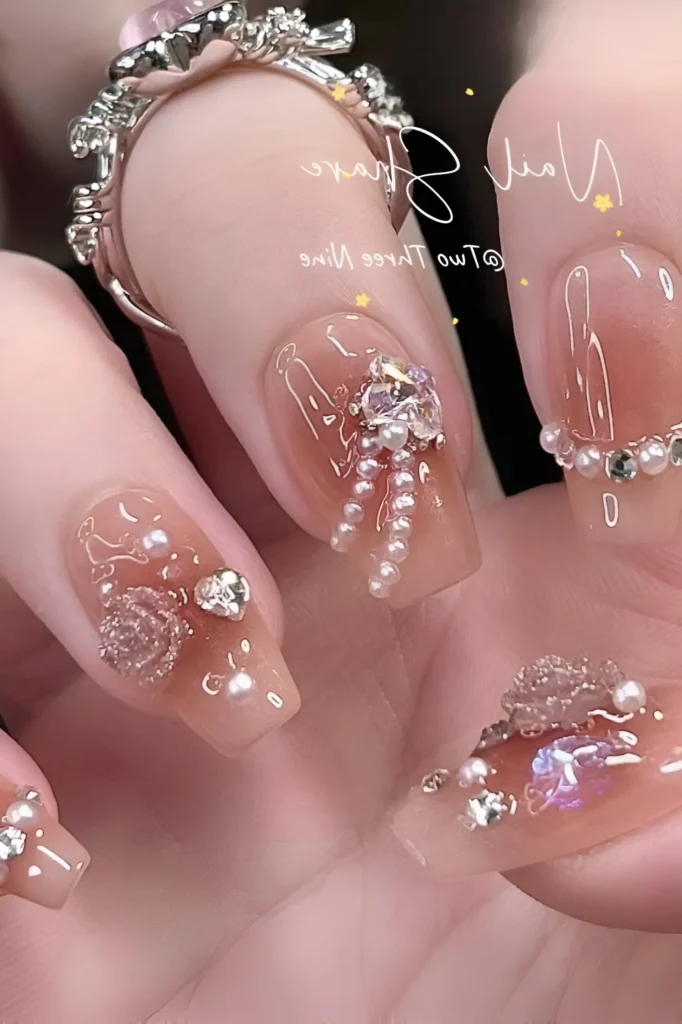 Luxury 3D nail art on translucent square nails, featuring sculpted bows, dangling pearl strands, clear rhinestones, and scattered pearl accents.