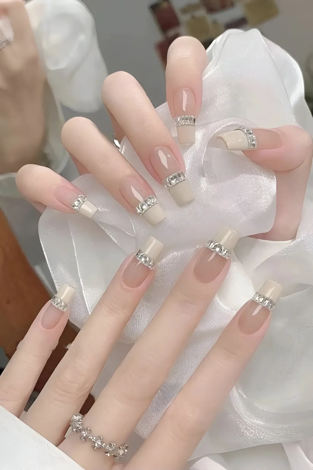 Cute long square nails with off-white French tips and horizontal crystal rhinestone band accent.