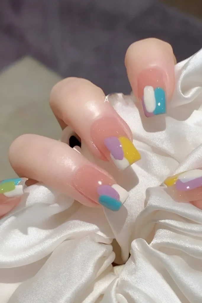 Cute nail design with sheer base and abstract color block French tips featuring overlapping pastel patches (lilac, yellow, blue, white); square shape.
