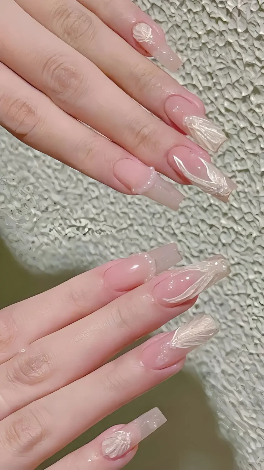 Cute long square nails with sheer pink base and sculpted pearly white 3D shell or wing accents.