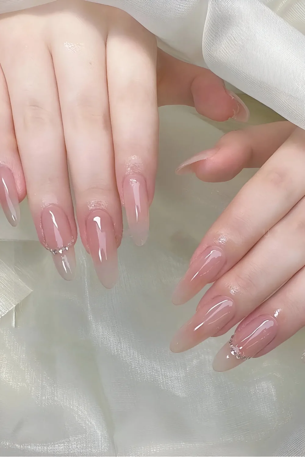 Cute long stiletto nails with sheer base and minimalist crystal arc at cuticle.