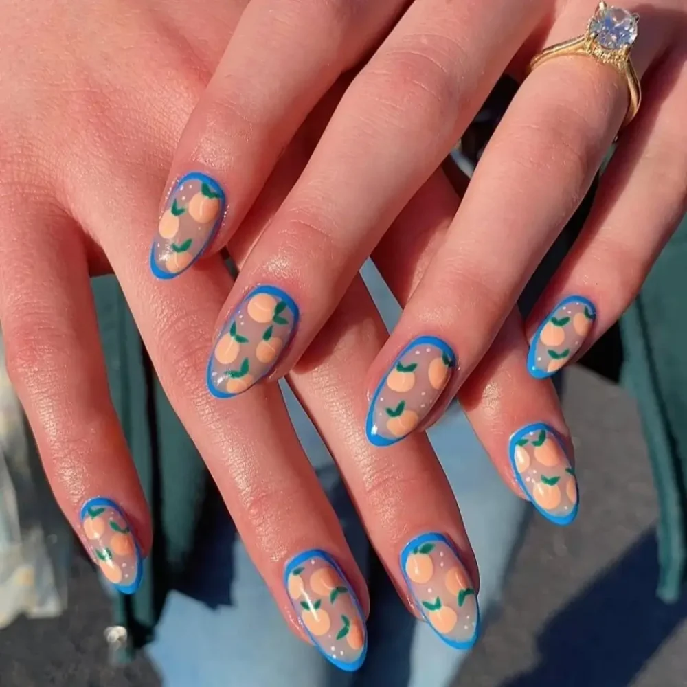 A cute peach pattern nail art design with a bold, contrasting blue outline on almond-shaped nails.