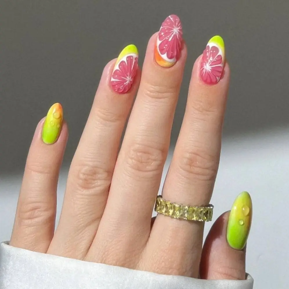 Vibrant citrus nail art featuring detailed pink grapefruit slices and 3D dewdrop effects on almond nails.