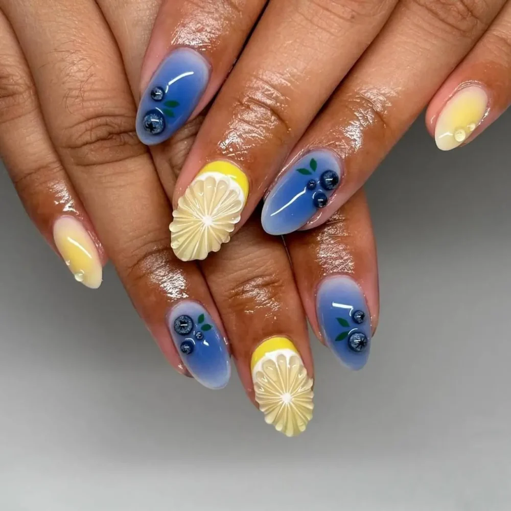 Detailed 3D lemon and blueberry fruit nail art on a blue and yellow gradient base.
