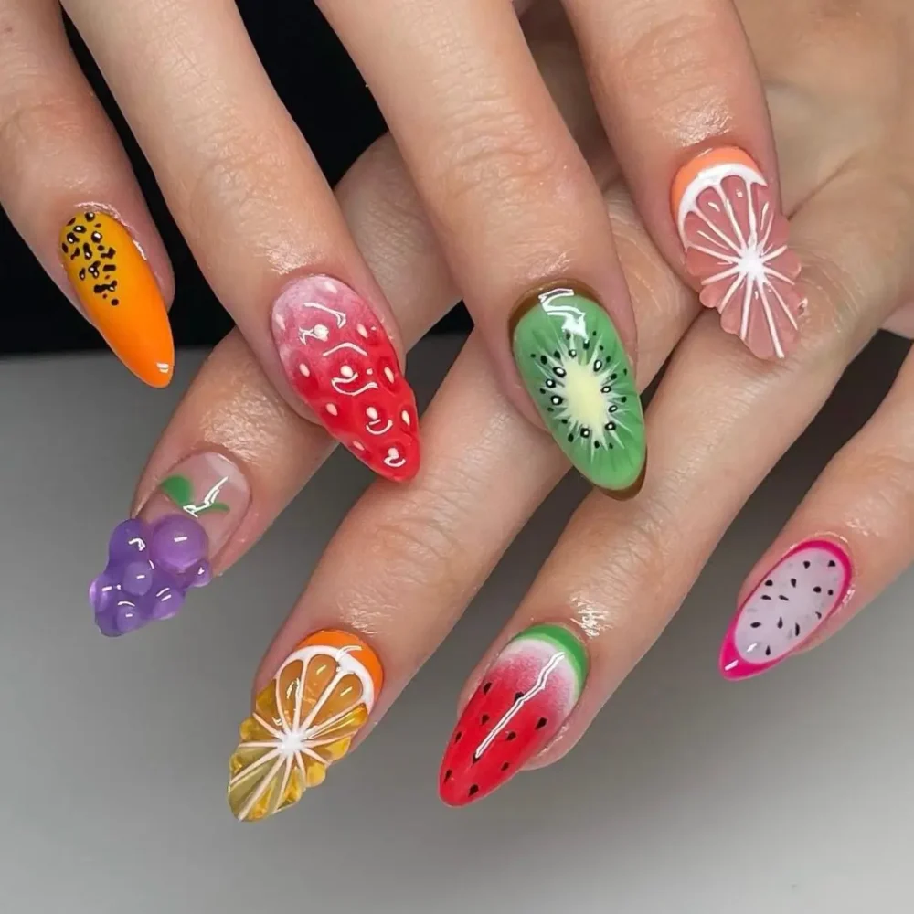 A hyper-realistic, 3D fruit salad nail art design on long almond-shaped nails.
